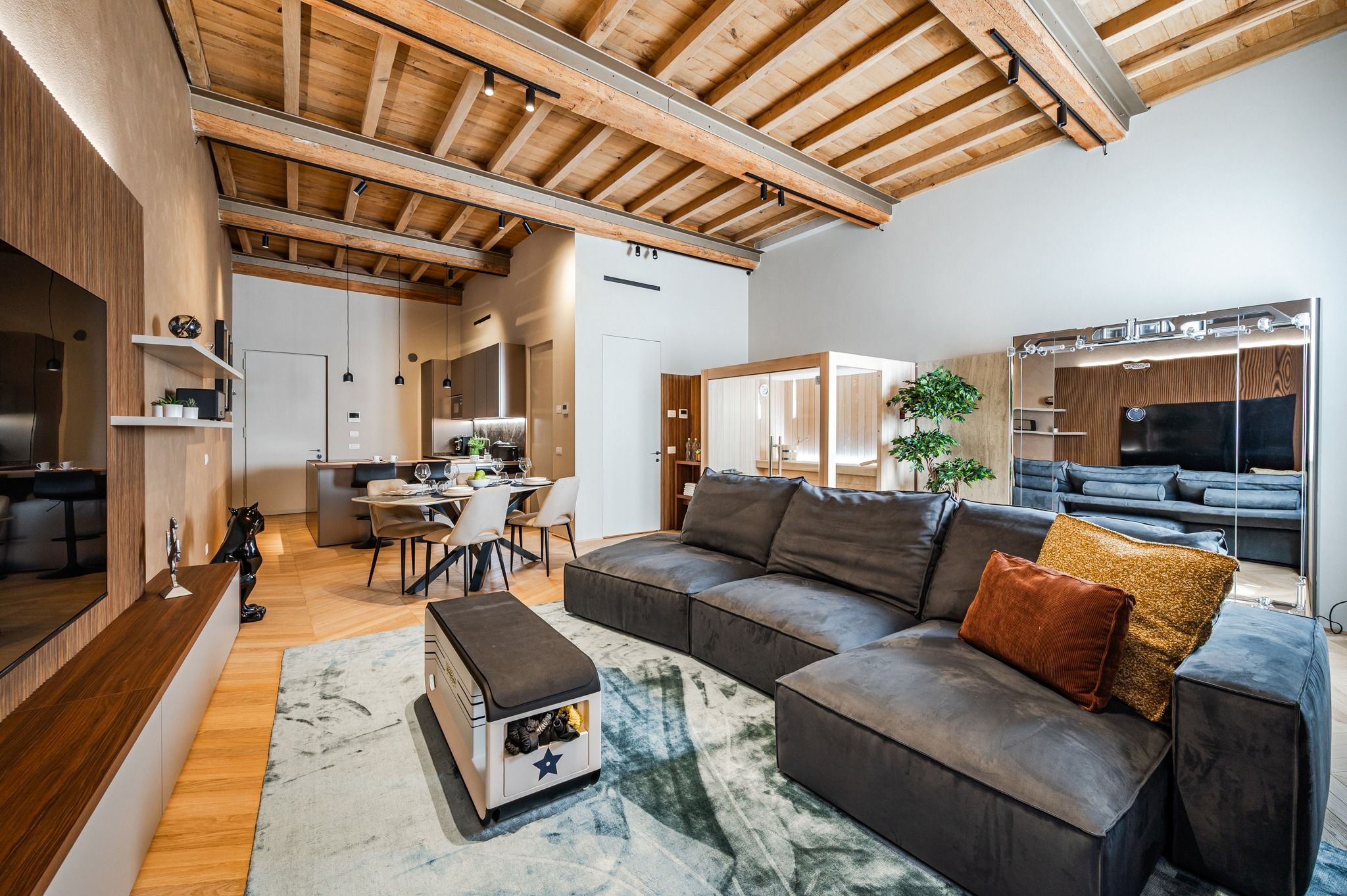 Il living completo: divano, tavolo apparecchiato e sauna sullo sfondo
